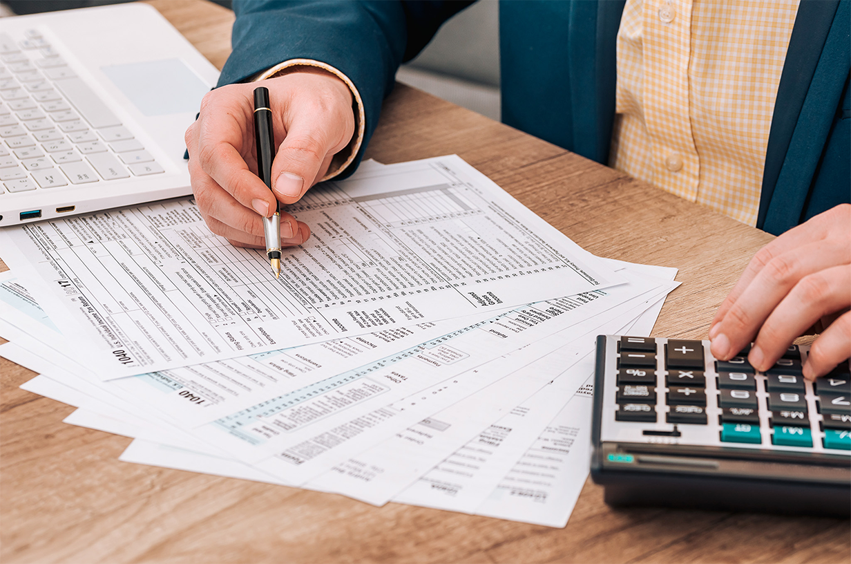 A person at a desk working on taxes and using a calculator.