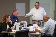 A group of individuals working and looking at documents.