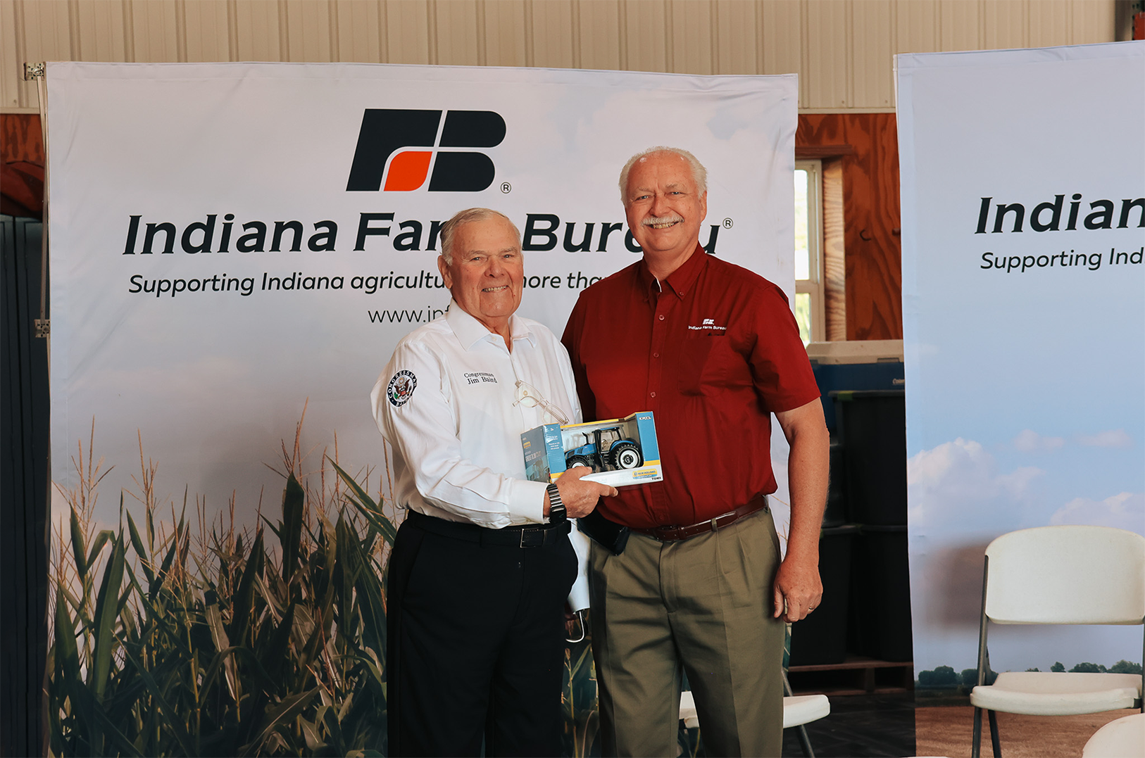 Two men smiling and exchanging a gift.