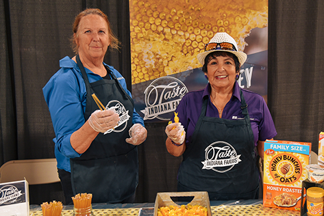 Two women holding samples of honey at Taste from Indiana Farms.