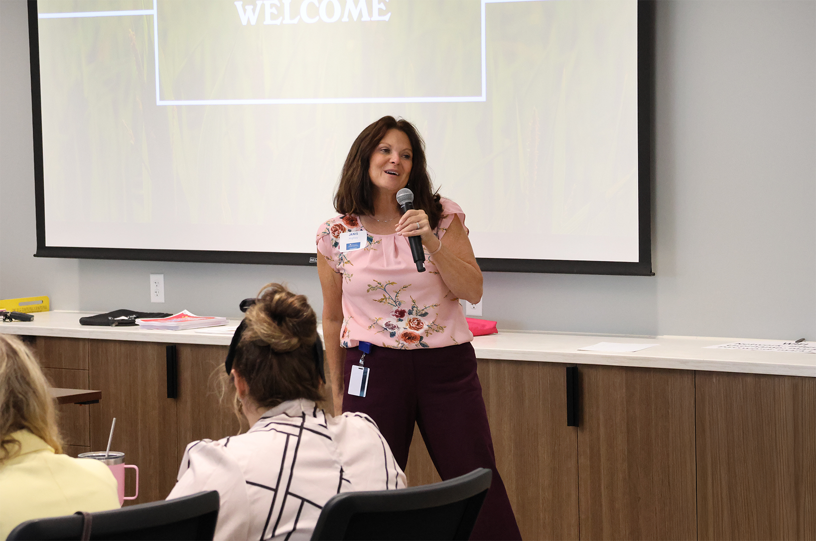 Woman presenting to a group using a microphone.